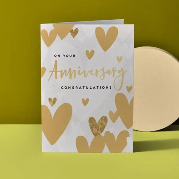 Anniversary congratulations card with gold heart pattern and elegant gold lettering displayed on a green background.